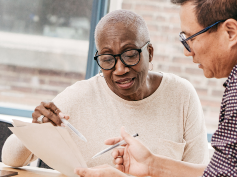 A woman writes a will with assistance.